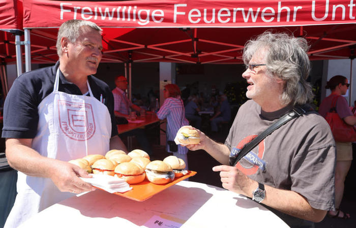 Beim Wäldchestag der Freiwilligen Feuerwehr Unterliederbach gehören Fischbrötchen dazu. Thomas Schott von der Feuerwehr bringt sie unters Volk; Ingbert Debus aus Unterliederbach greift gerne zu. FOTO: Maik Reuß